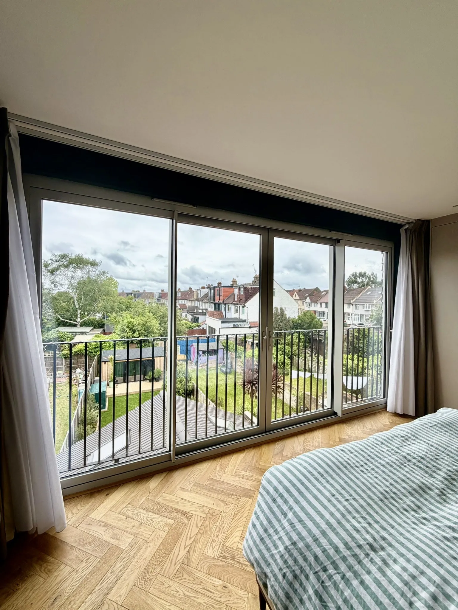 Loft bedroom with full-height glazing and elevated neighbourhood views