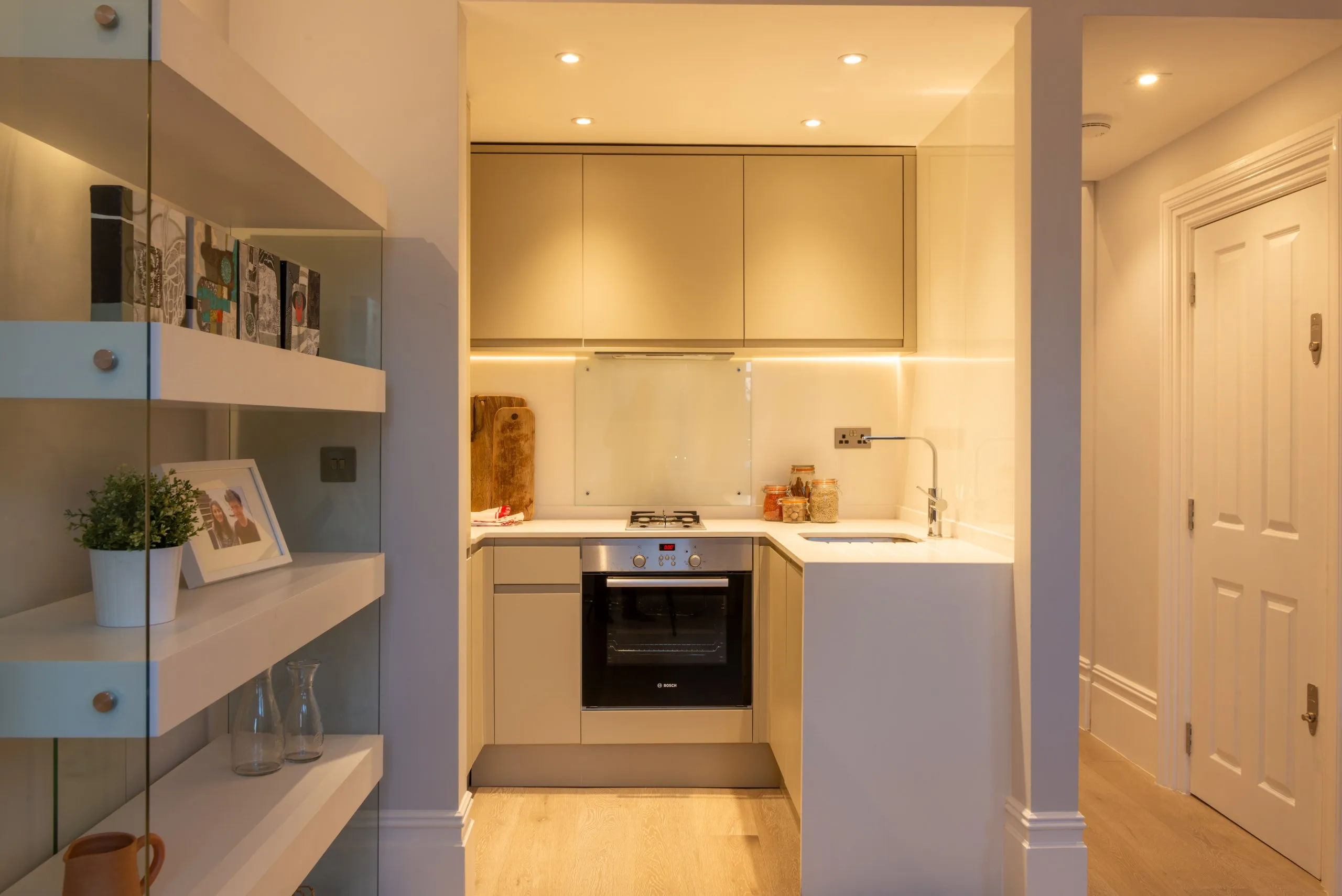 Compact refurbished kitchen with integrated appliances and fitted shelving