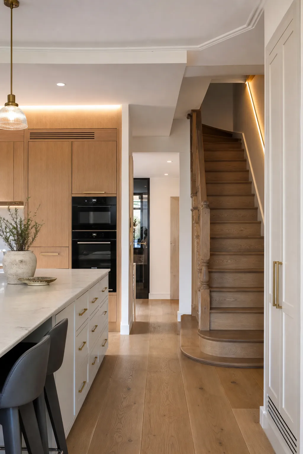 Renovated kitchen and hallway with coordinated joinery, lighting, and a restored staircase