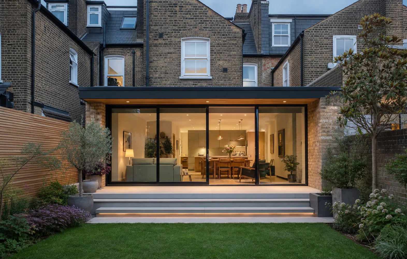 Glazed rear extension with warm interior lighting and a landscaped garden