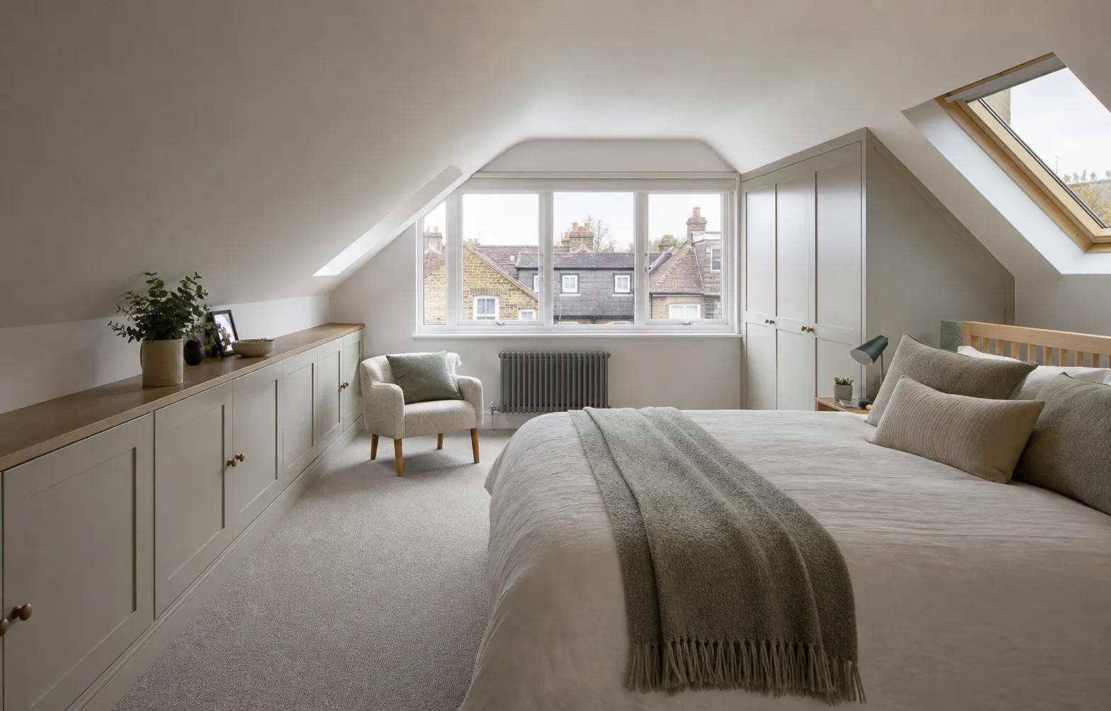 Loft bedroom with fitted eaves storage, rooflight, and city views